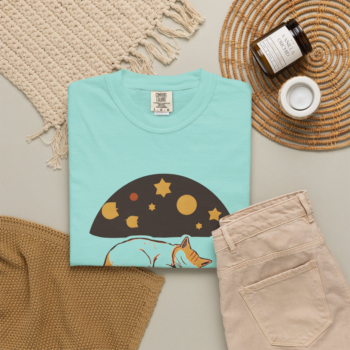 Lunch Break Read tee in Chalky Mint, folded in a styled flat lay with a woven mat, candle and khaki shorts — sleeping cat print on the front
