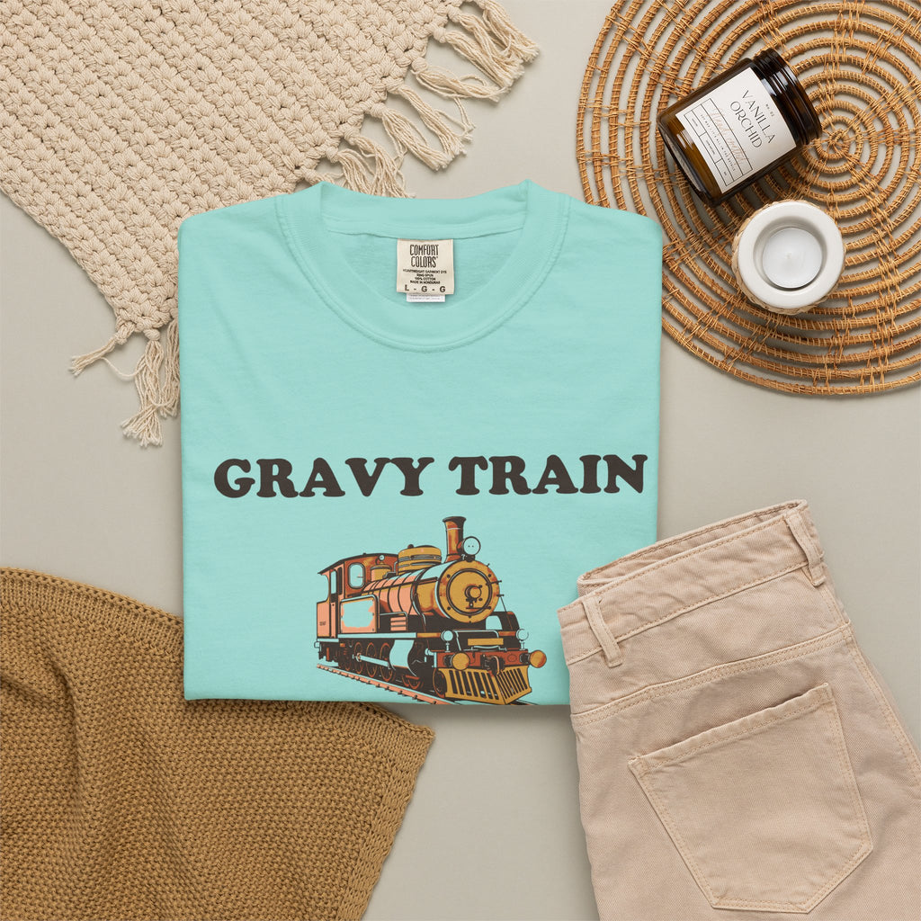 Gravy Train Conductor tee in Chalky Mint, folded in a styled flat lay with a woven mat, candle and khaki shorts — locomotive print on the front