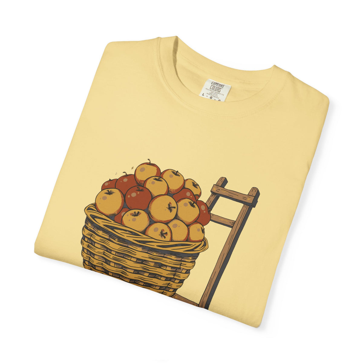 Peaked in the Orchard tee in Butter yellow, folded — close view of the apple basket print